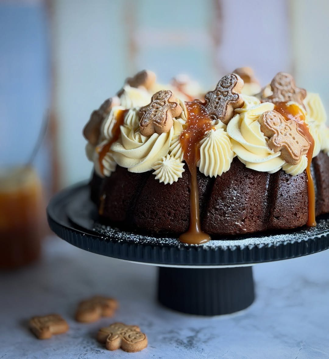 12 Beautiful Christmas Cake Ideas That Rival Bakery Work 1 A dark bundt cake decorated with white frosting, caramel sauce, and small gingerbread man cookies.