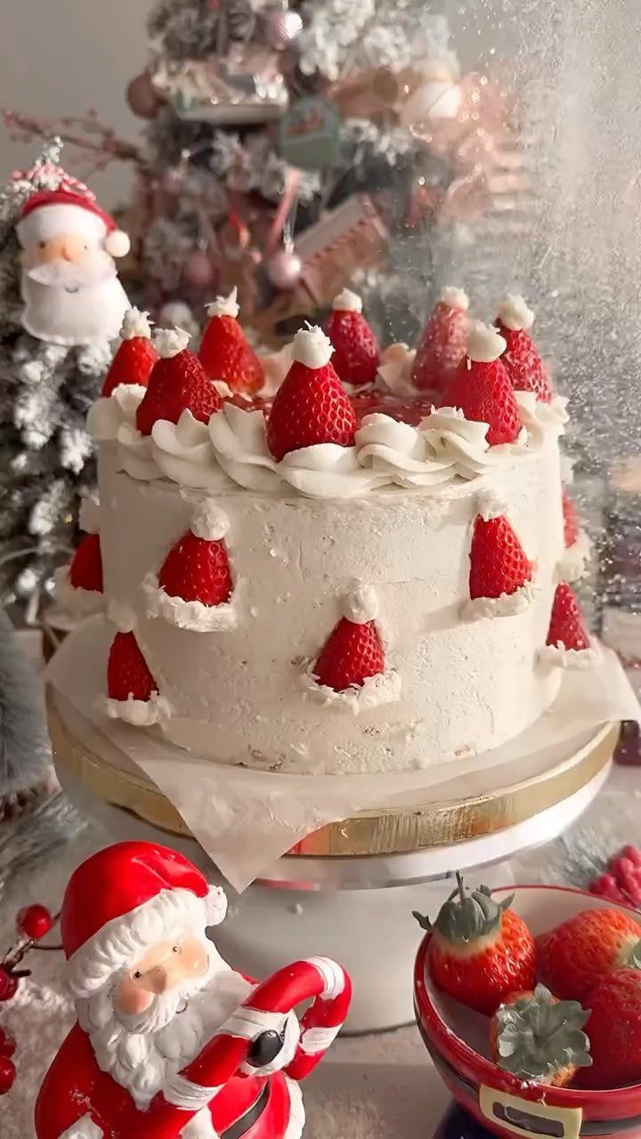 12 Beautiful Christmas Cake Ideas That Rival Bakery Work 9 A white frosted cake decorated with strawberry Santa hats and festive Christmas decorations.