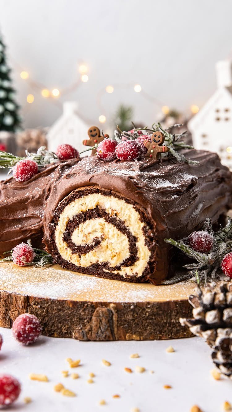 12 Beautiful Christmas Cake Ideas That Rival Bakery Work 3 Chocolate yule log cake with cream swirl, red berries, and gingerbread men on a wooden platter.