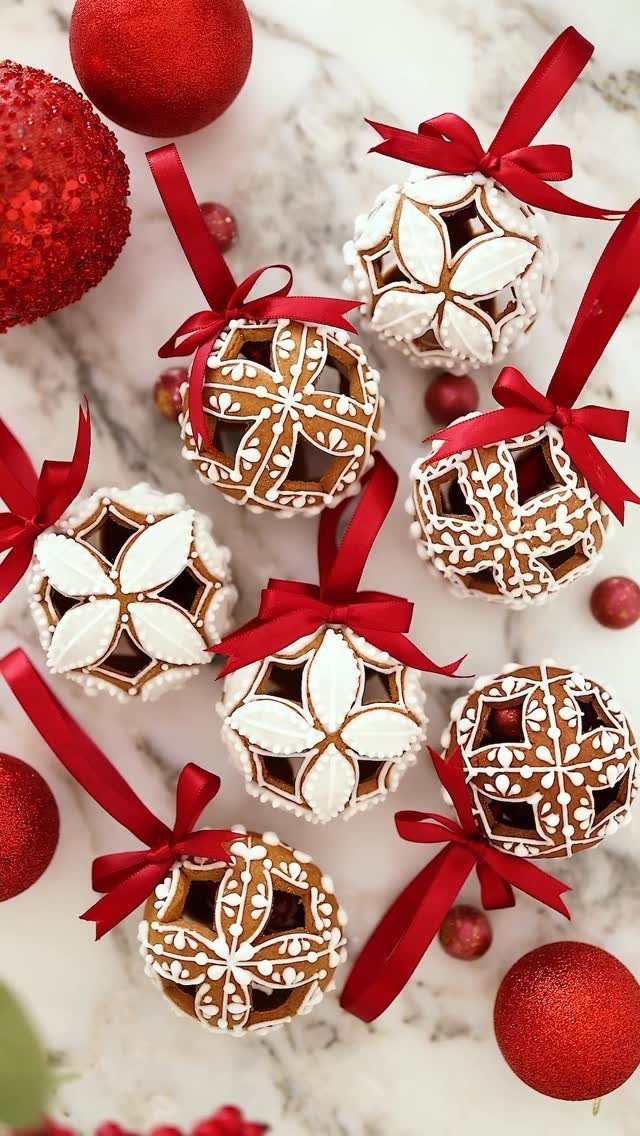 14 Beautiful Christmas Tree Decorations and How to Style Them 1 Gingerbread sphere ornaments with white icing patterns and red ribbons on a marble surface.