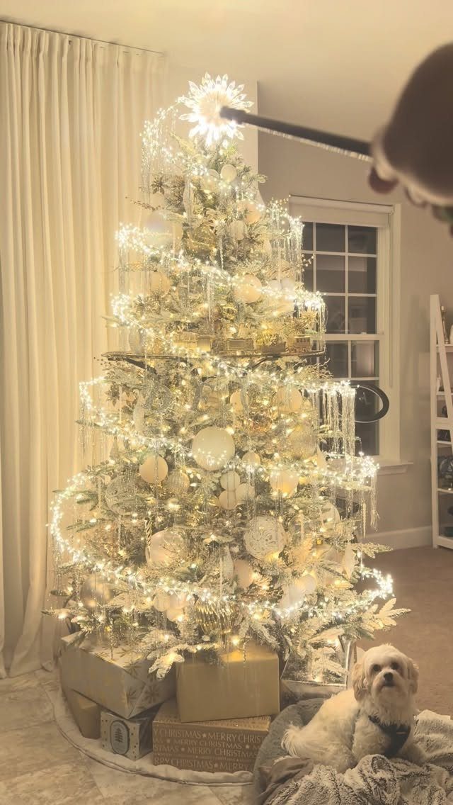 14 Beautiful Christmas Tree Decorations and How to Style Them 11 A glowing Christmas tree decorated with gold and white ornaments and lights near a small dog.