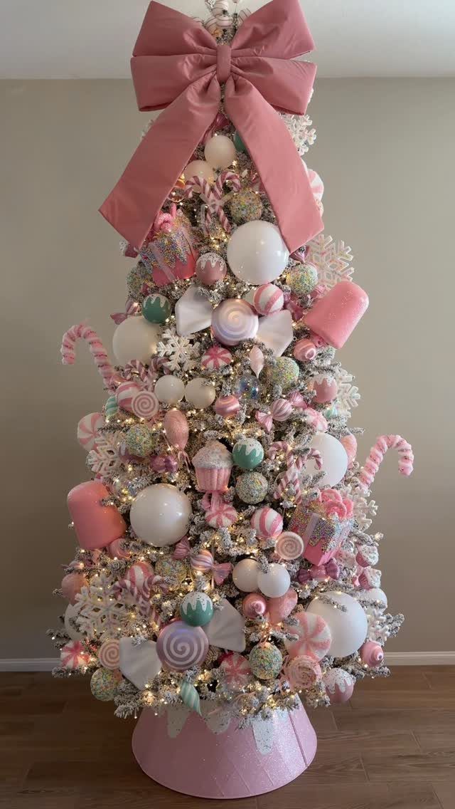 14 Beautiful Christmas Tree Decorations and How to Style Them 7 A Christmas tree decorated with pastel pink, white, and mint green candy-themed ornaments and a large pink bow.