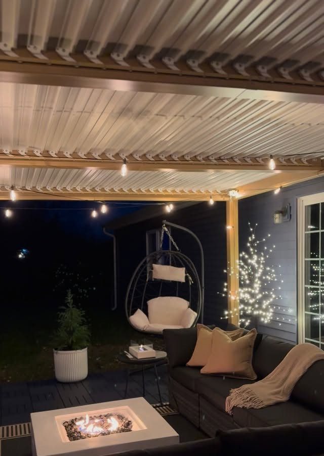 17 Cheap Yard Ideas for a Better Front or Back Garden 3 Outdoor patio at night with a fire pit, sofa, and hanging egg chair under string lights.