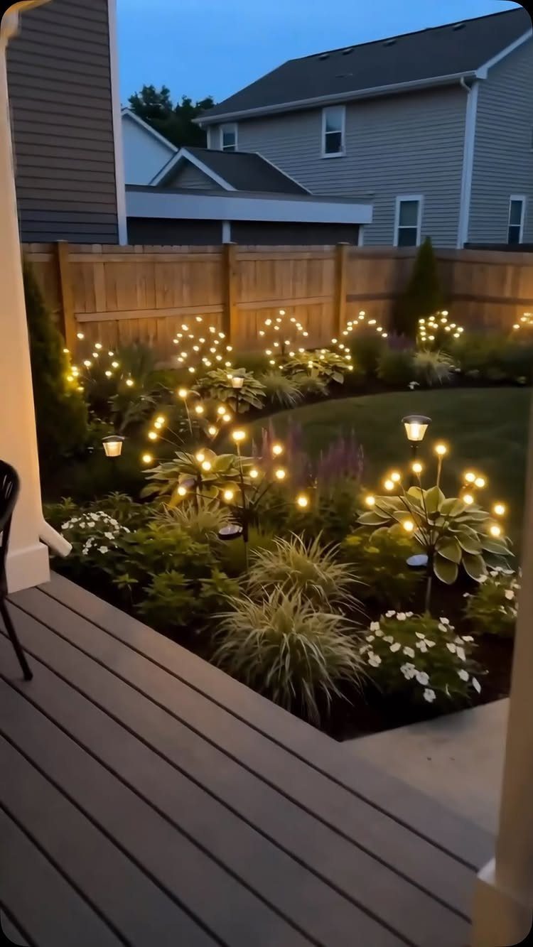 17 Cheap Yard Ideas for a Better Front or Back Garden 14 Solar lights illuminating various green plants and white flowers in a backyard garden bed.
