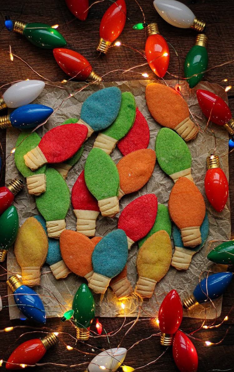13 Christmas Cookie Decorations Ideas for Your Holiday Baking 7 Light bulb shaped cookies in colorful icing arranged on parchment paper with glowing string lights.