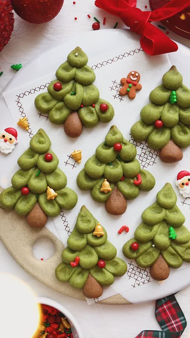 13 Christmas Cookie Decorations Ideas for Your Holiday Baking 2 Green Christmas tree cookies decorated with tiny red and gold ornaments on a white plate.