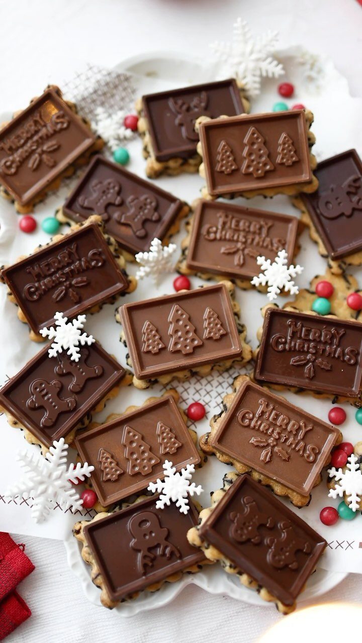 13 Christmas Cookie Decorations Ideas for Your Holiday Baking 3 Chocolate embossed rectangular cookies arranged on a white plate with snowflake decorations and colorful candies.