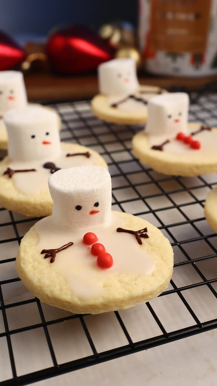 13 Christmas Cookie Decorations Ideas for Your Holiday Baking 1 Melted snowman cookies with marshmallow heads and red candy buttons on a cooling rack.