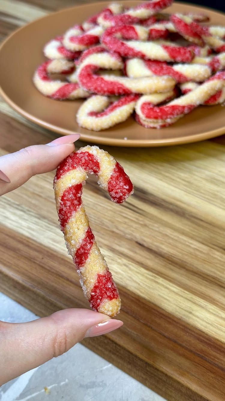 13 Christmas Cookie Decorations Ideas for Your Holiday Baking 11 A hand holding a red and white striped candy cane shaped sugar cookie.