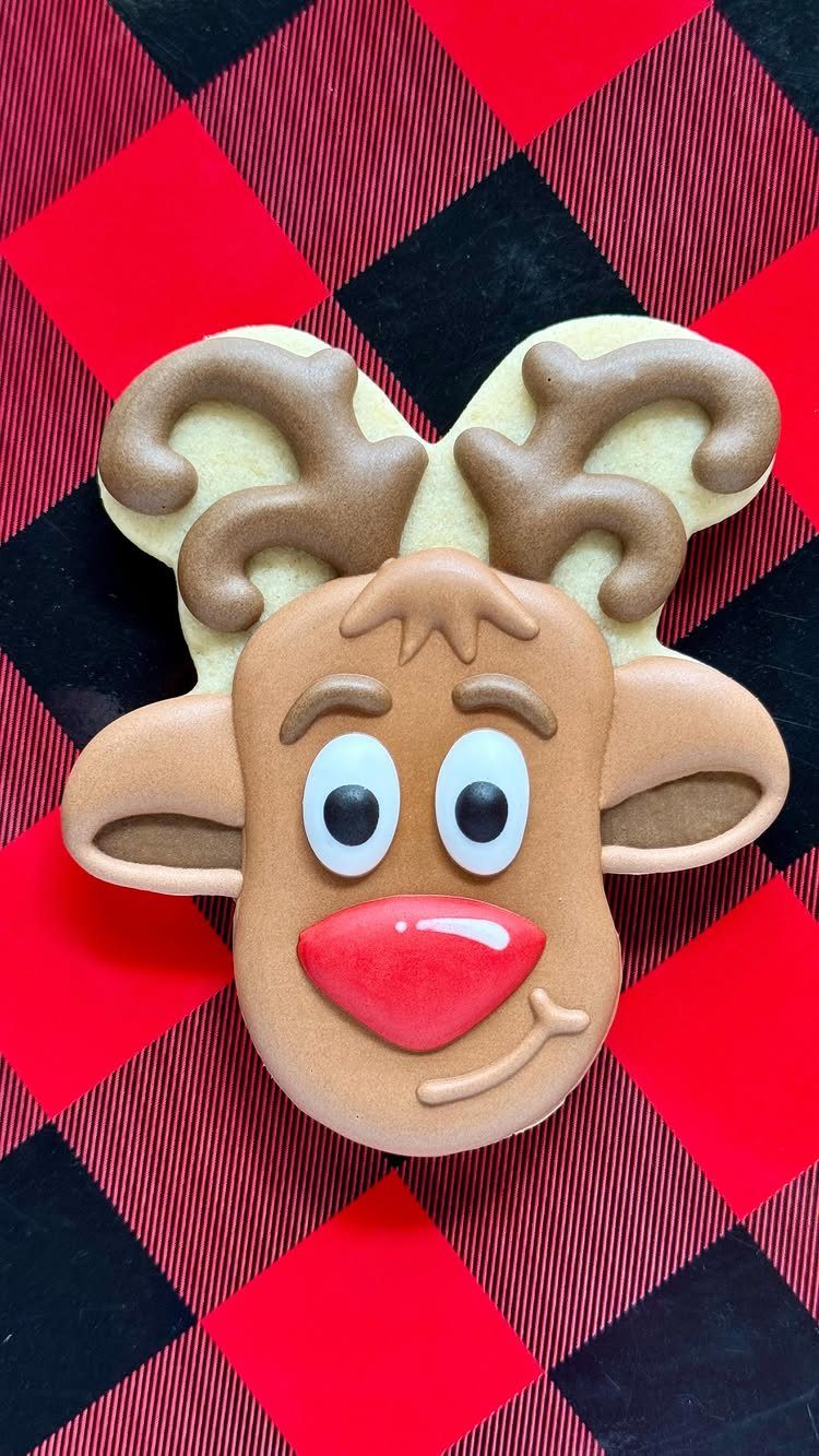 13 Christmas Cookie Decorations Ideas for Your Holiday Baking 4 Rudolph the reindeer face decorated sugar cookie on a red and black plaid background.