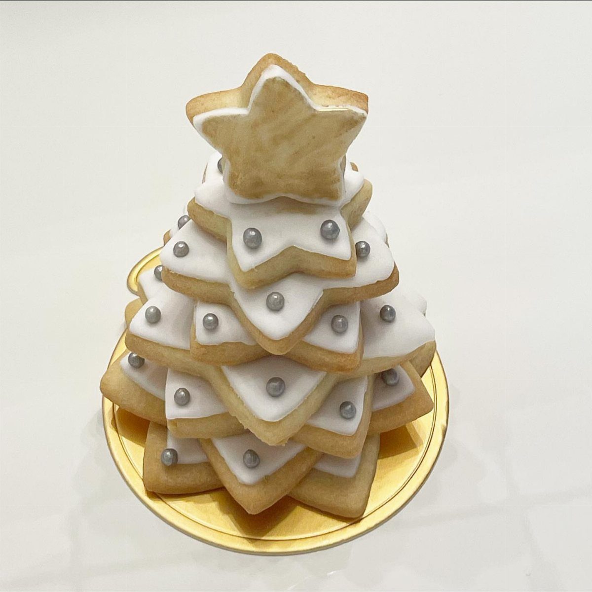 13 Christmas Cookie Decorations Ideas for Your Holiday Baking 12 Stacked star-shaped cookies with white icing and silver pearls arranged like a Christmas tree.