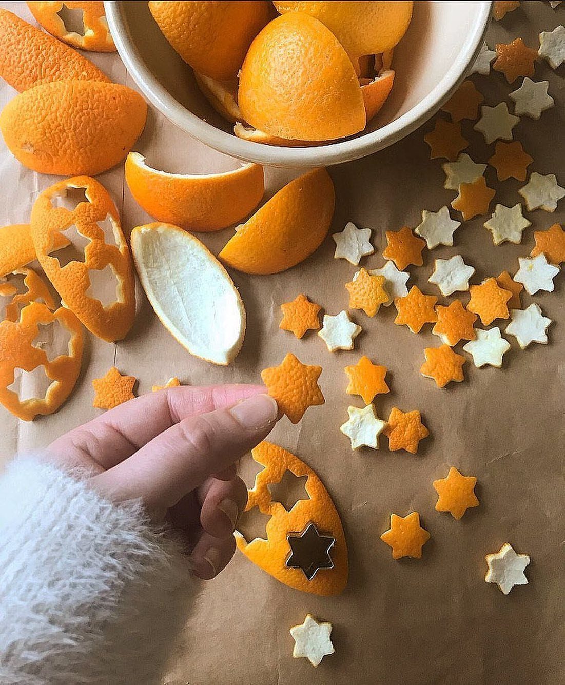 Christmas Craft for Adults: 5 Projects That Belong to the Evening 5 A hand picks up a star-shaped orange peel cutout among many other small star shapes.
