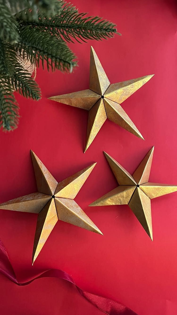 Christmas Craft for Adults: 5 Projects That Belong to the Evening 1 Three gold three-dimensional paper star ornaments on a red background with pine branches.