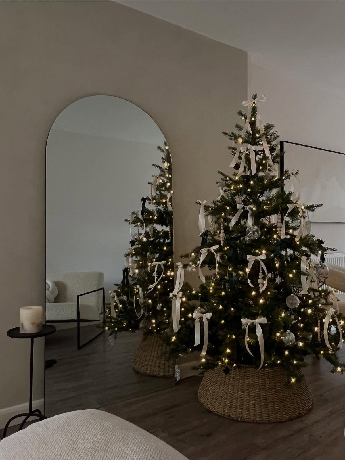 Christmas Decor Aesthetic: 13 Looks to Try This Season 6 A decorated Christmas tree with white ribbons and warm lights reflected in an arched mirror.