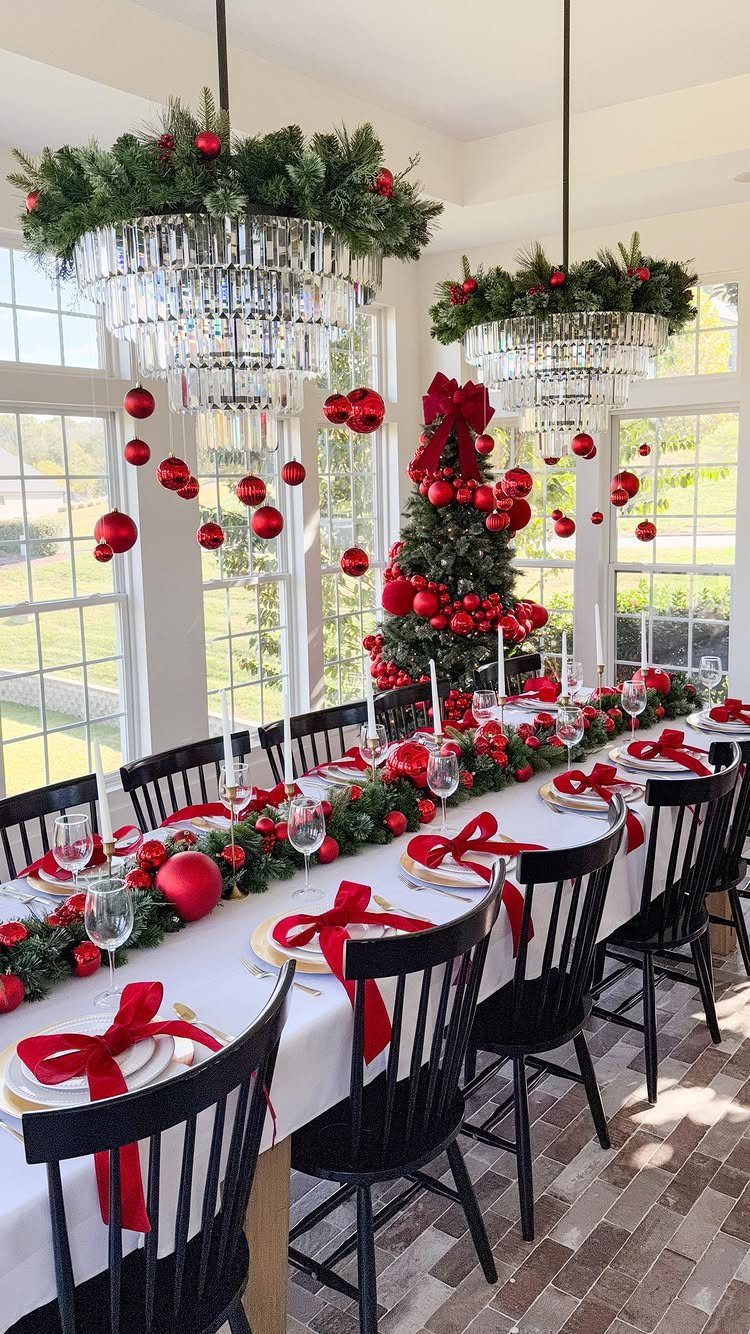Christmas Dinner and Table Decorations: 9 Ideas for Setting the Scene 4 A festive Christmas dining table featuring greenery, red ornaments, and layered plates with red bow napkins.