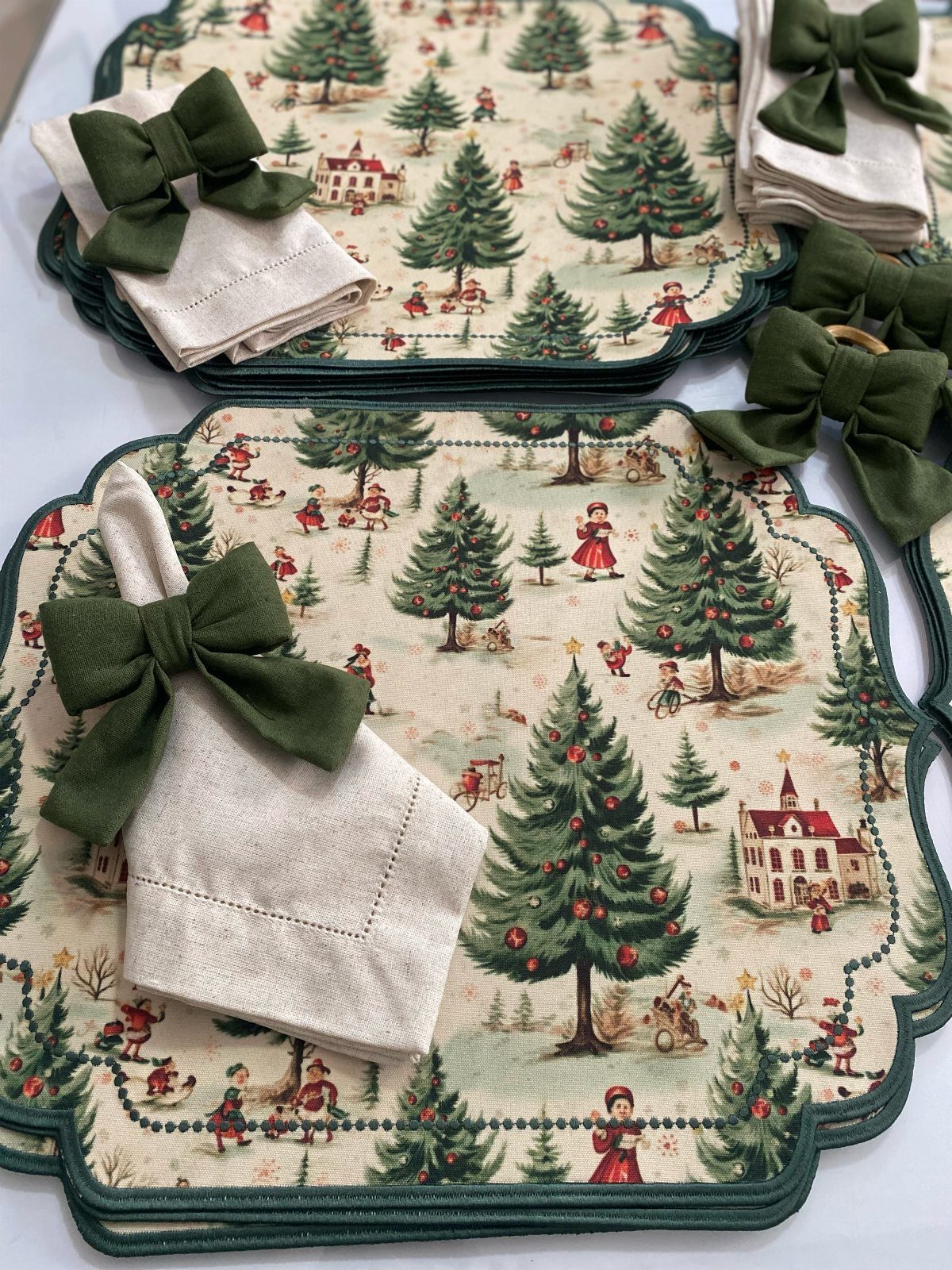 Christmas Dinner and Table Decorations: 9 Ideas for Setting the Scene 8 Christmas patterned placemats with cream napkins tied in dark green velvet bows.