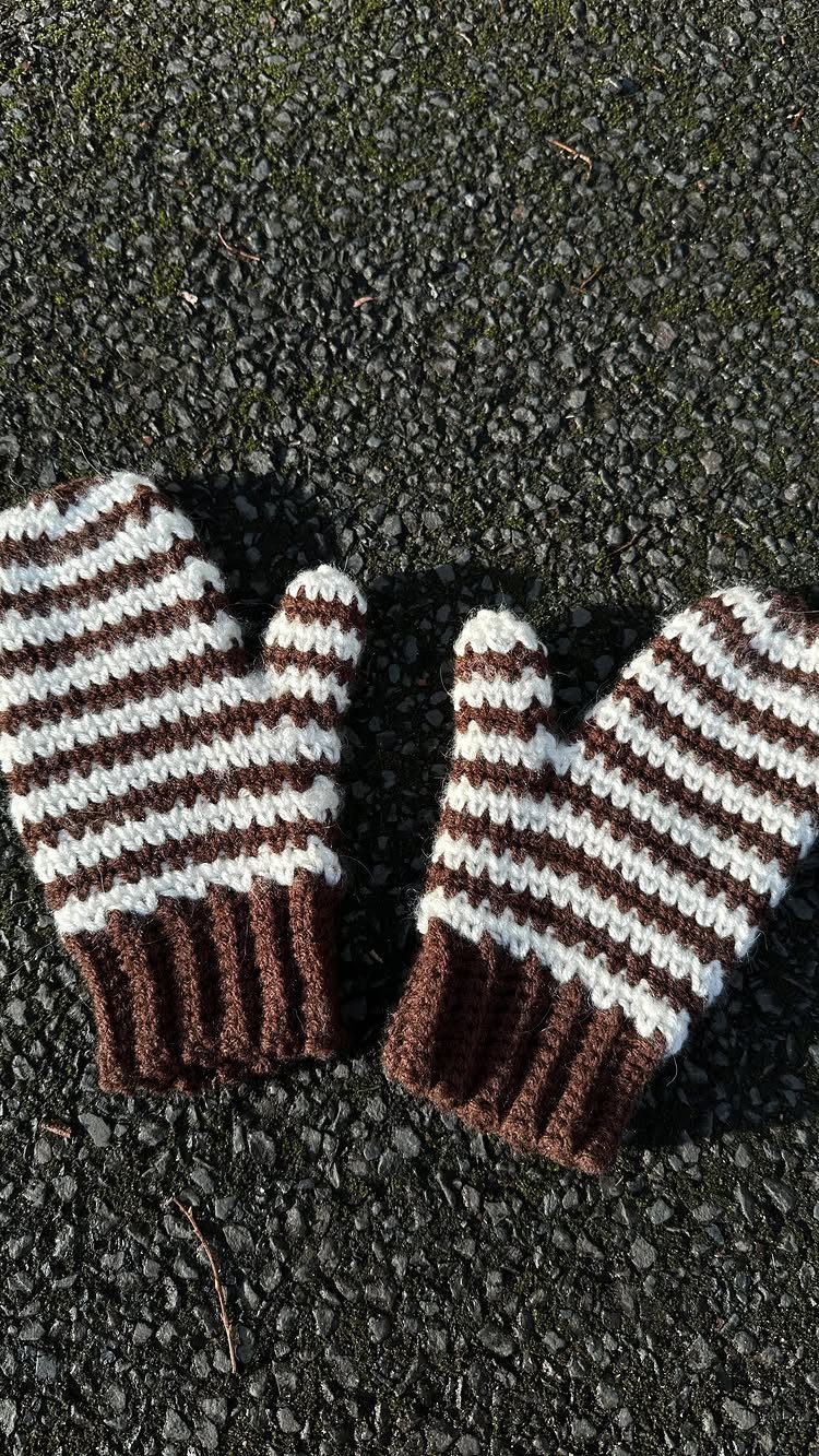 18 Christmas Gift Crochet Ideas for Everyone on Your List 3 Brown and white striped crochet mittens resting on a dark asphalt ground.