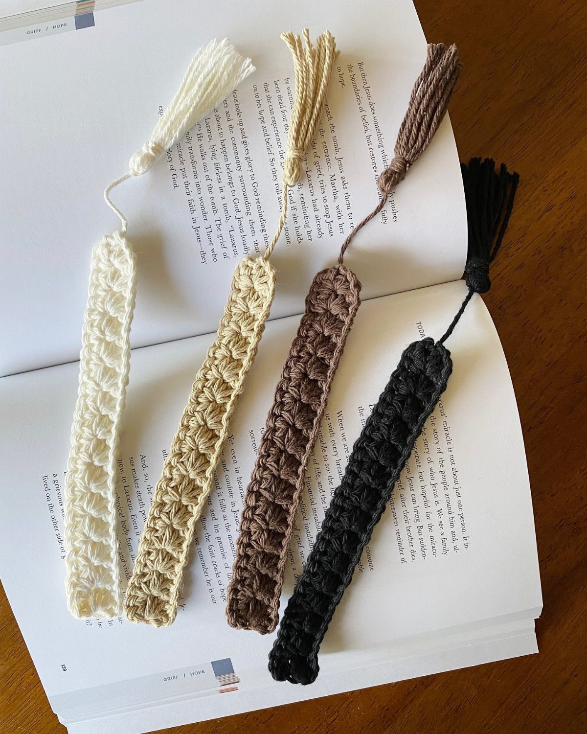18 Christmas Gift Crochet Ideas for Everyone on Your List 10 Four colorful crochet bookmarks with tassels resting on the pages of an open book.