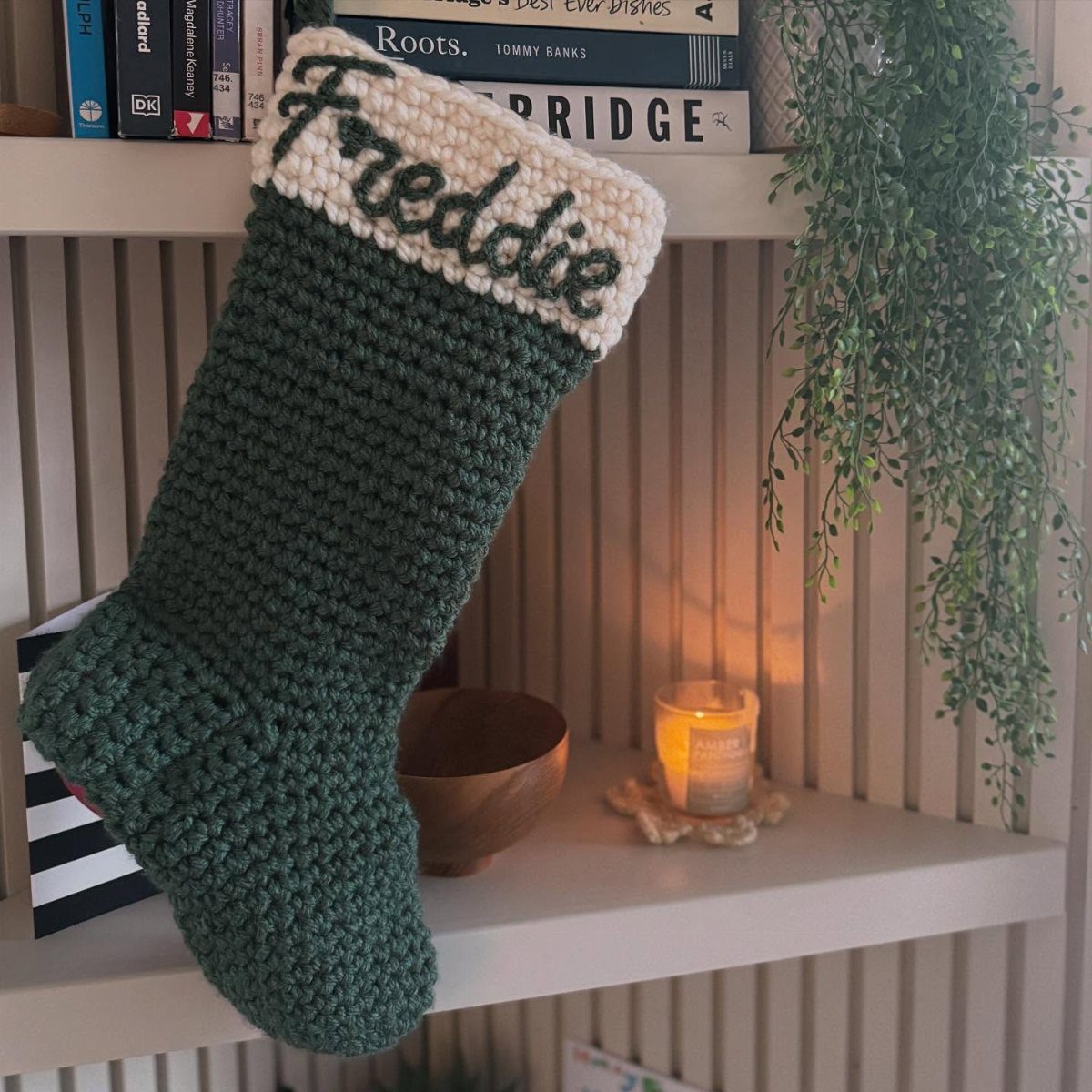 18 Christmas Gift Crochet Ideas for Everyone on Your List 17 A dark green crocheted Christmas stocking with the name Freddie on a white cuff.