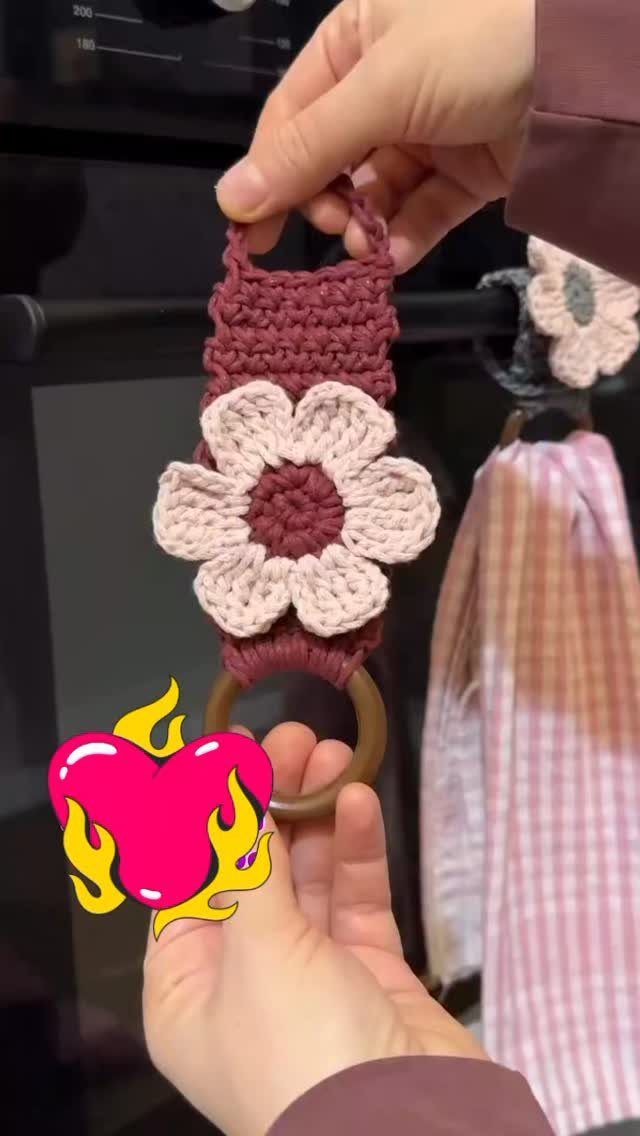 18 Christmas Gift Crochet Ideas for Everyone on Your List 13 Hands holding a maroon crochet towel holder decorated with a large pink flower and wooden ring.