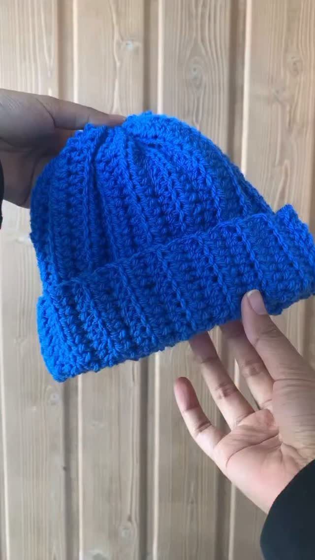 18 Christmas Gift Crochet Ideas for Everyone on Your List 15 Hands holding a bright blue chunky crochet beanie against a light wood background.