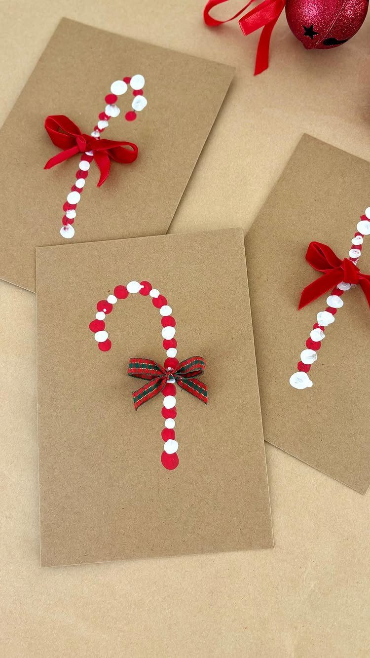 Three brown paper Christmas cards decorated with red and white pom-pom candy canes and bows.