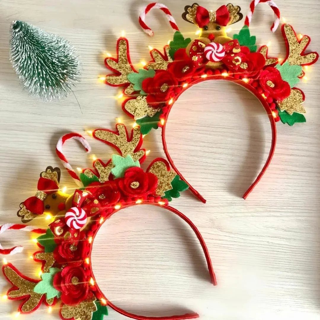 Two red reindeer headbands with glittery antlers and glowing LED lights on wood.