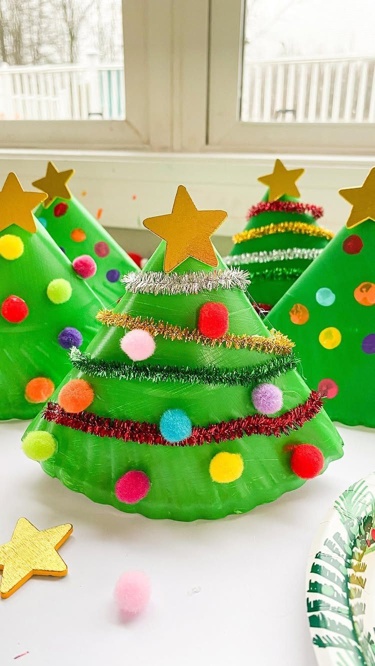 Green paper plate Christmas trees decorated with colorful pom-poms and gold stars.