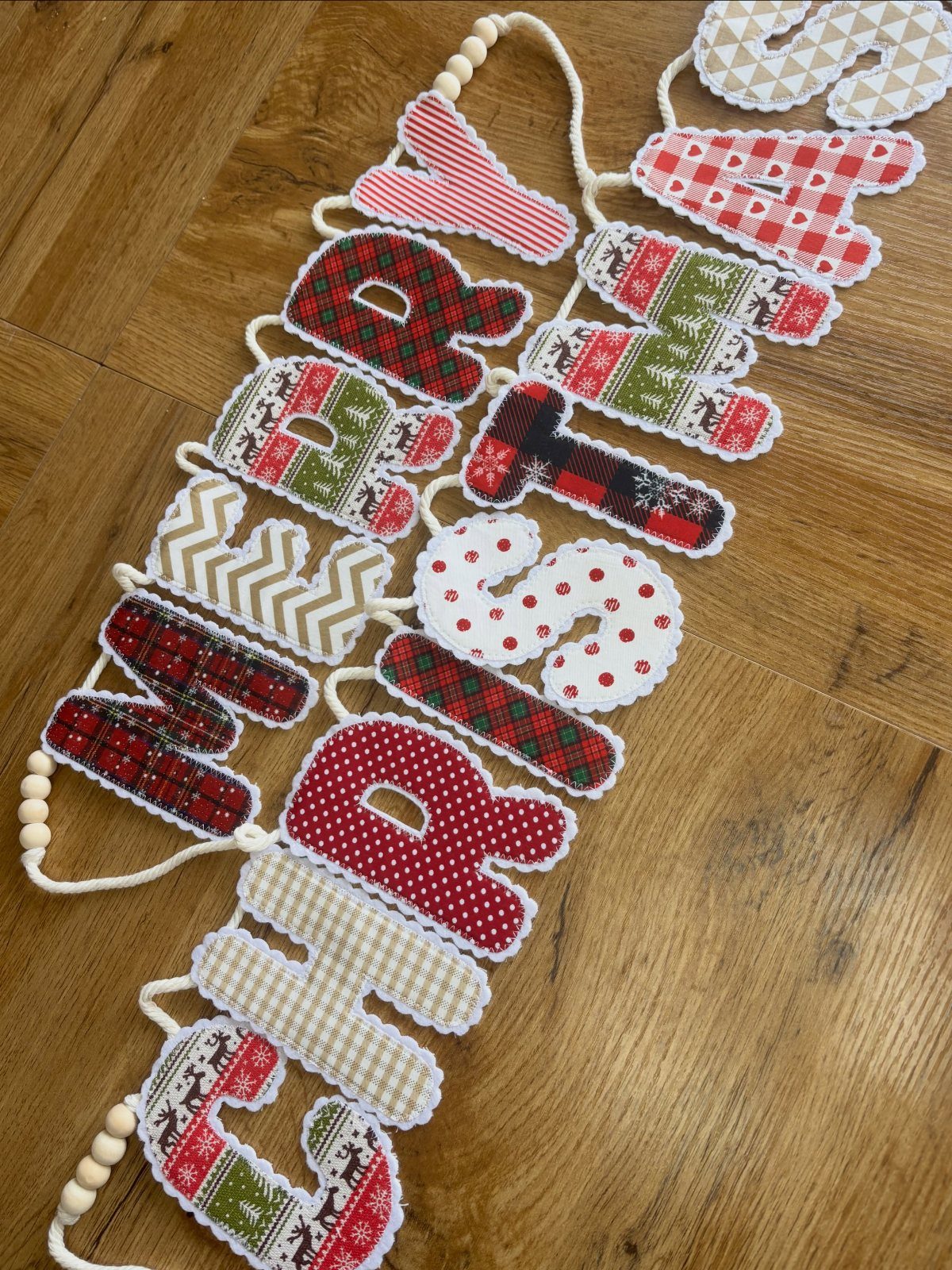 16 Christmas Sewing Projects That Cover the Whole Holiday 16 Fabric letters spelling Merry Christmas in festive patterns on a wooden surface.