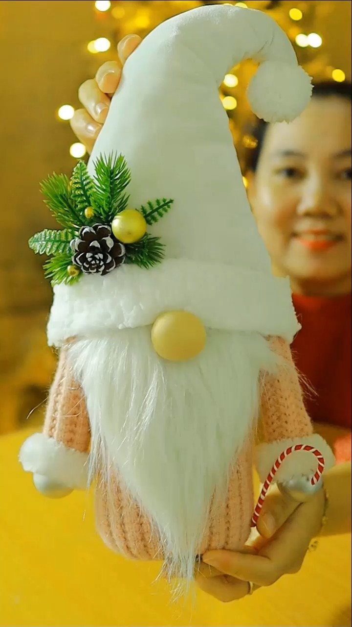 16 Christmas Sewing Projects That Cover the Whole Holiday 12 A person holding a handmade Christmas gnome with a white hat and peach knitted body.