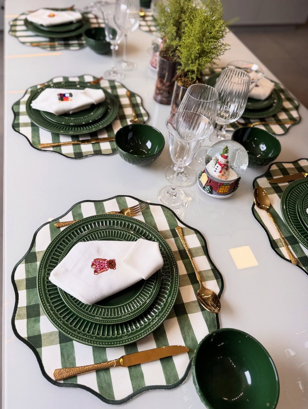 16 Christmas Sewing Projects That Cover the Whole Holiday 11 Dining table set with green and white checkered placemats, dark green plates, and gold cutlery.