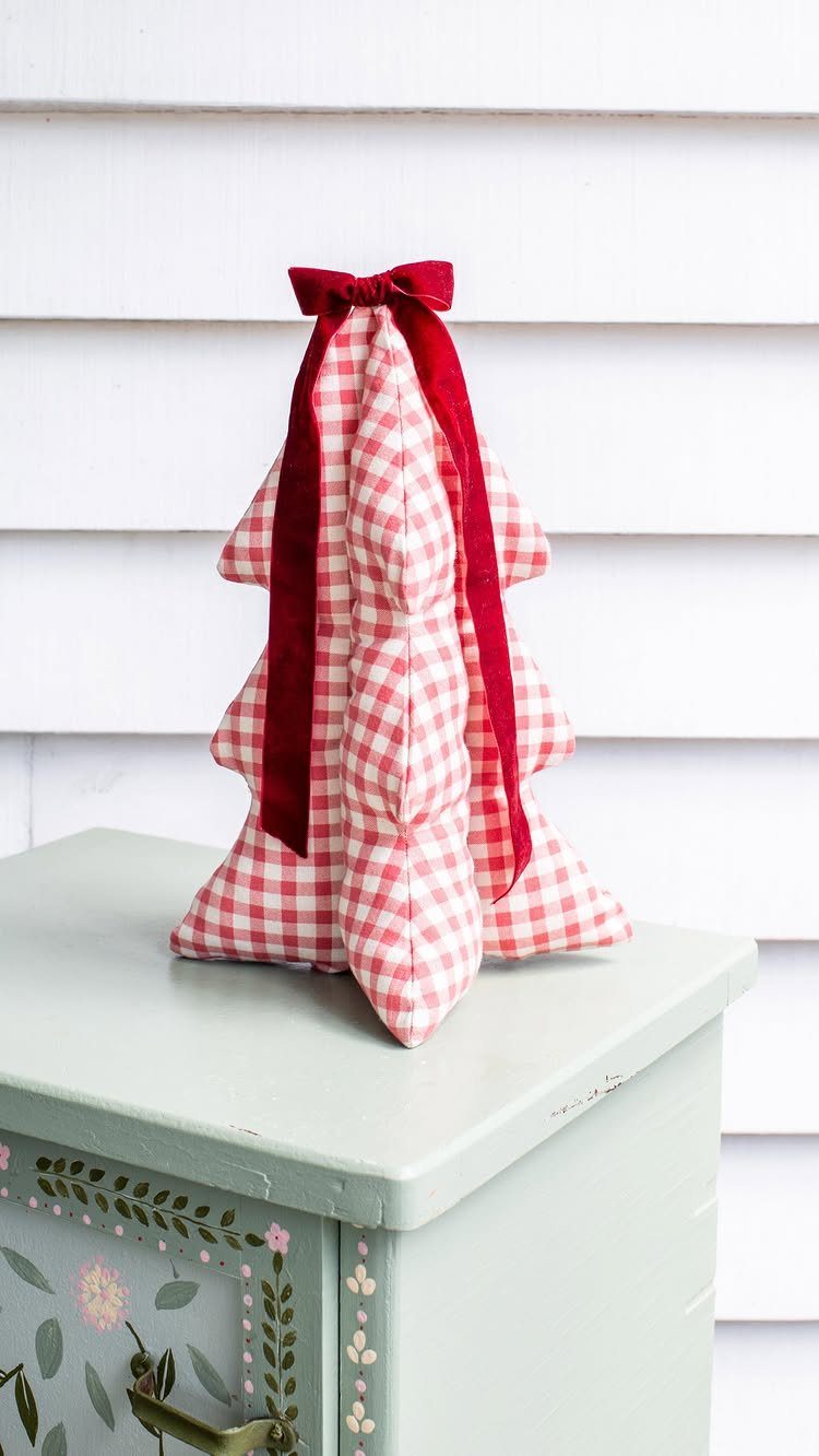 16 Christmas Sewing Projects That Cover the Whole Holiday 13 A red and white gingham fabric tree ornament with a large red velvet bow on top.