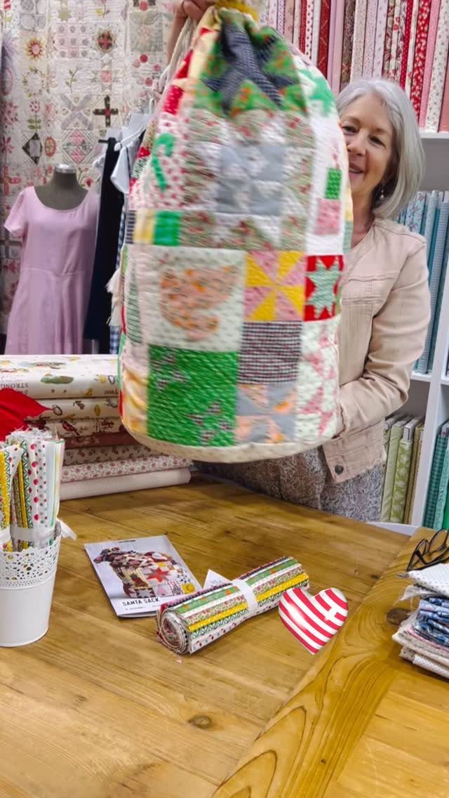 16 Christmas Sewing Projects That Cover the Whole Holiday 6 A woman holding a large patchwork fabric sack in a sewing room.
