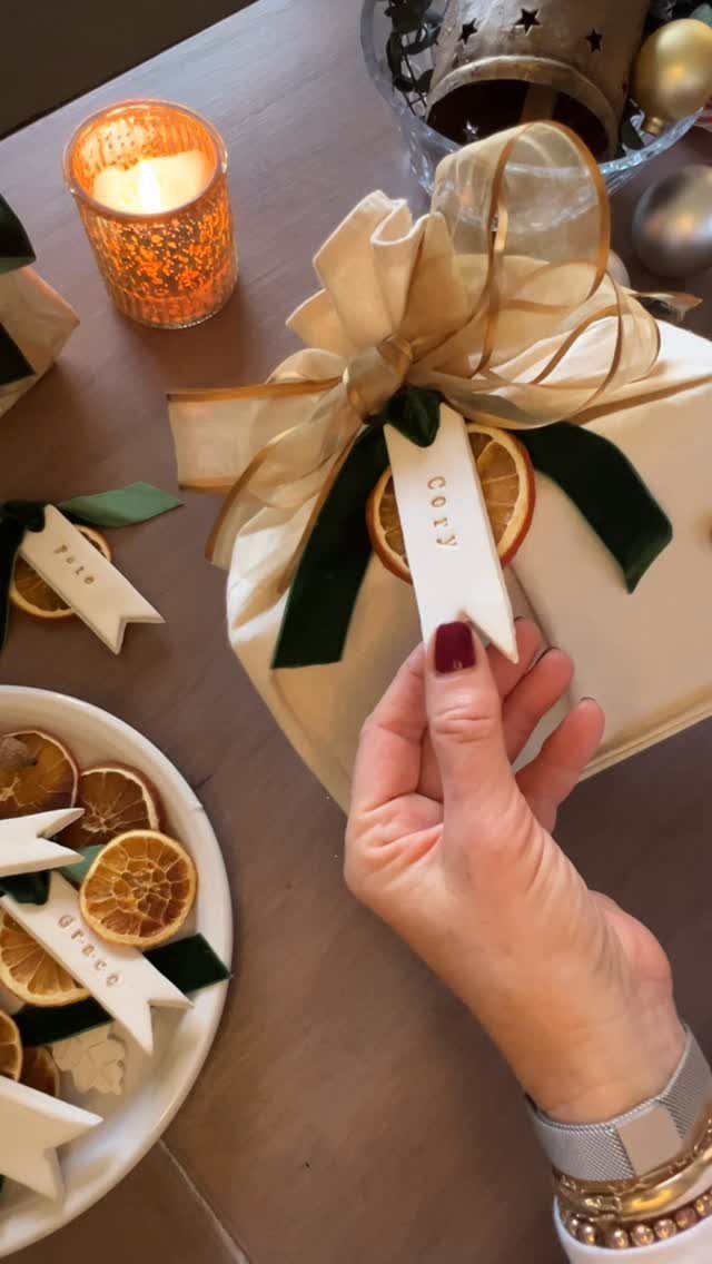 13 Christmas Table Decoration Ideas for Every Style 6 A hand holding a white pennant-shaped place card attached to a festive napkin arrangement.