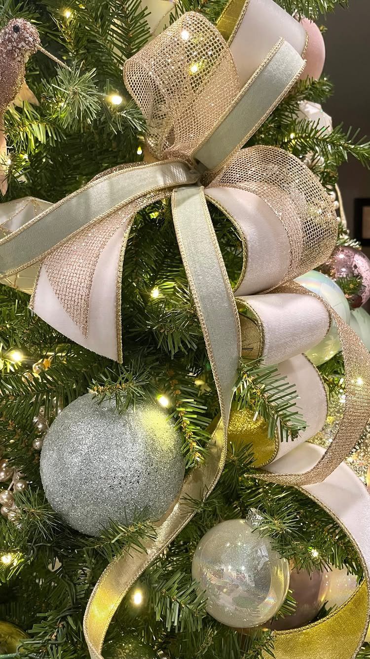 Christmas Tree Ribbon: 18 Styling Ideas That Work 4 A large light green and gold ribbon bow decorating a lit Christmas tree with ornaments.