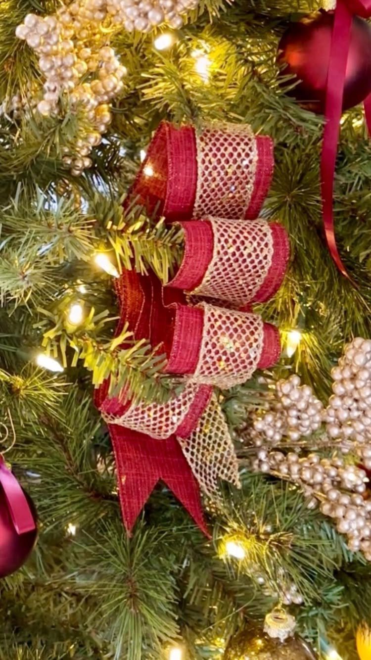 Christmas Tree Ribbon: 18 Styling Ideas That Work 2 Glittered red and gold ribbon woven through green Christmas tree branches with white berries.