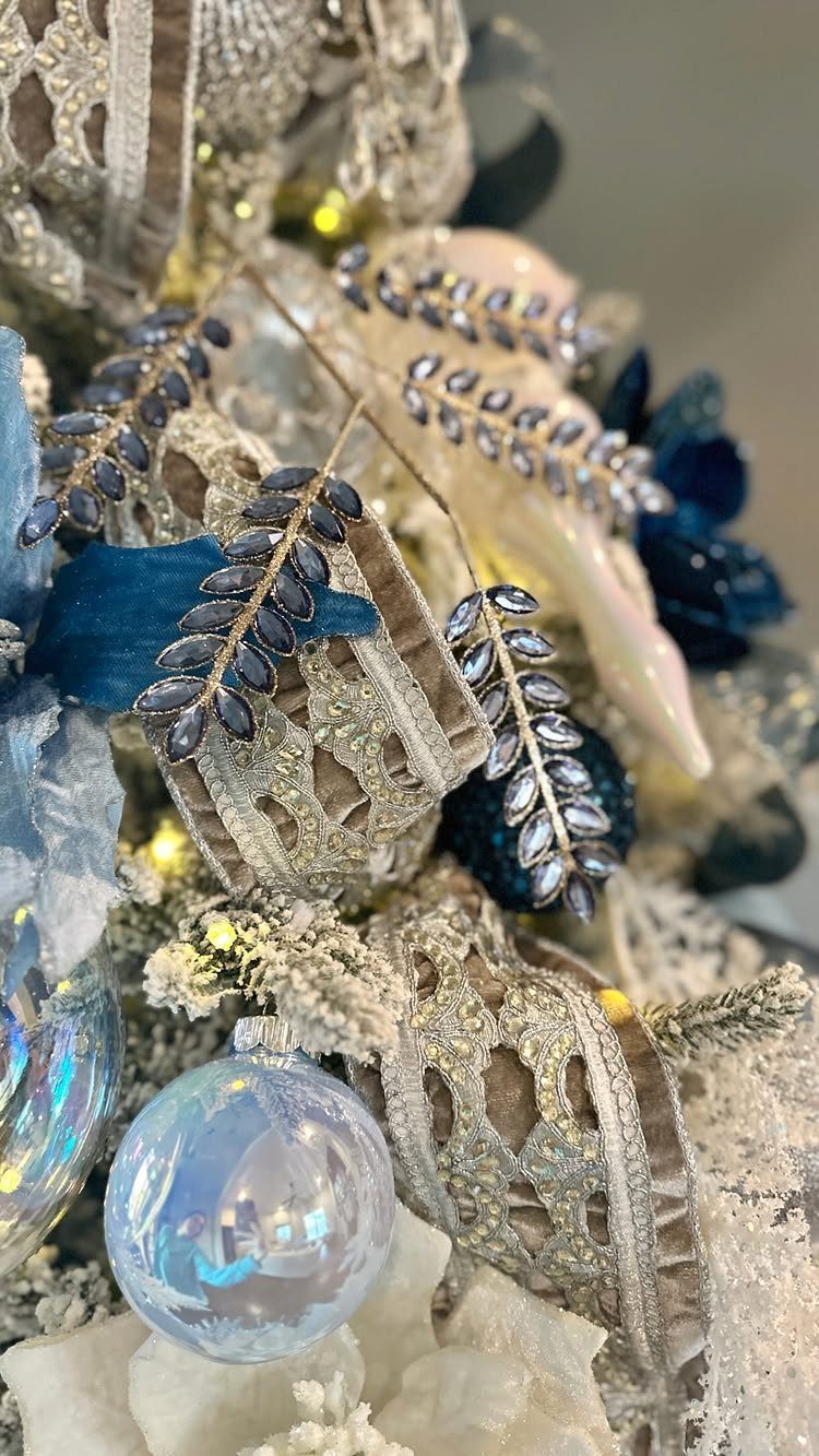 Christmas Tree Ribbon: 18 Styling Ideas That Work 9 Silver lace ribbon and blue ornaments decorating a frosted Christmas tree branch.