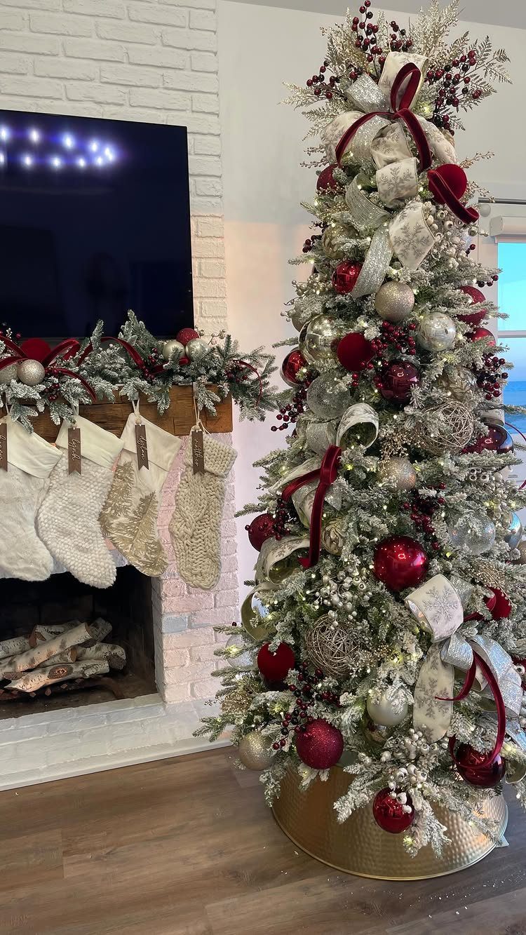 Christmas Tree Ribbon: 18 Styling Ideas That Work 3 Decorated Christmas tree with red and gold ribbons, red ornaments, and frosted branches near a fireplace.
