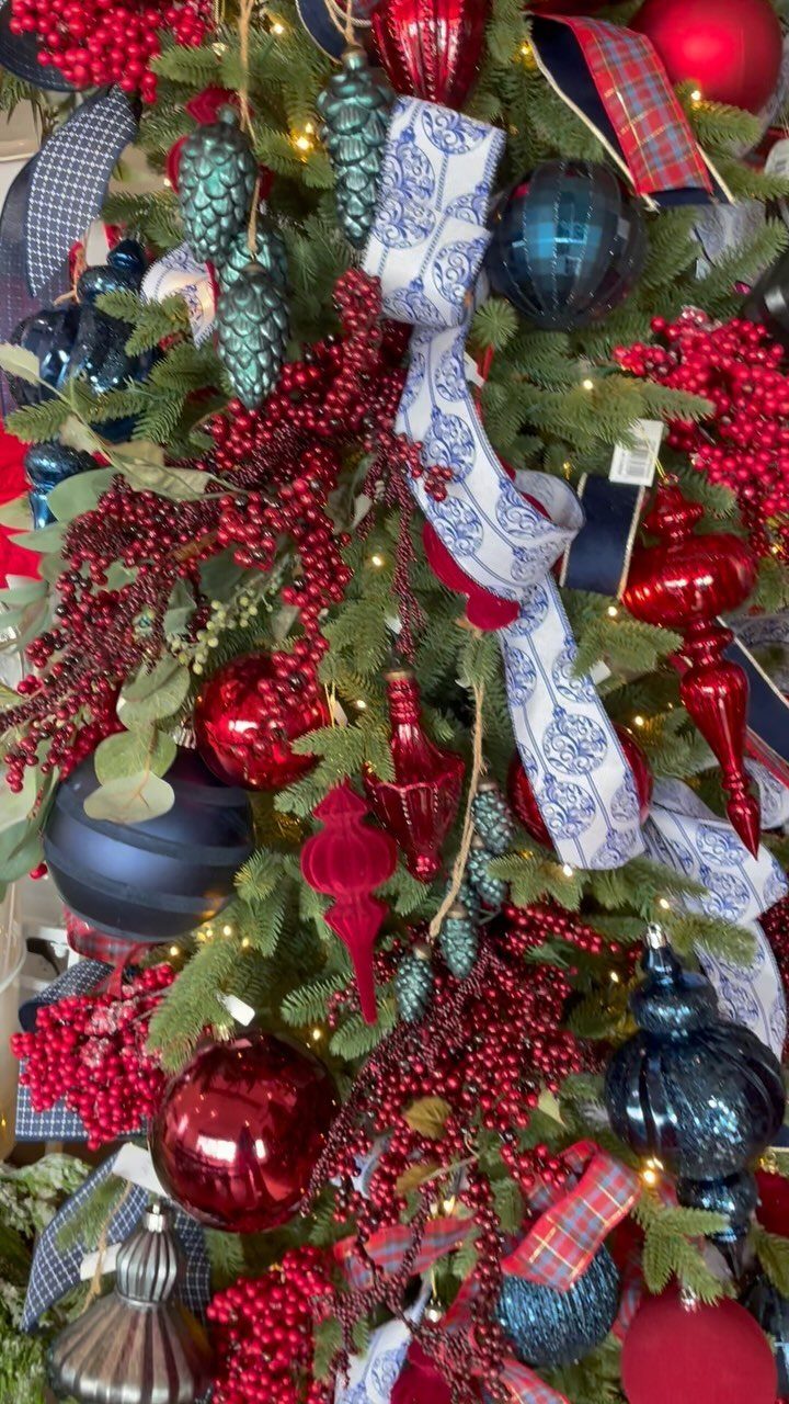 Christmas Tree Ribbon: 18 Styling Ideas That Work 16 Decorated Christmas tree with red and blue ornaments, red berries, and patterned white ribbon.