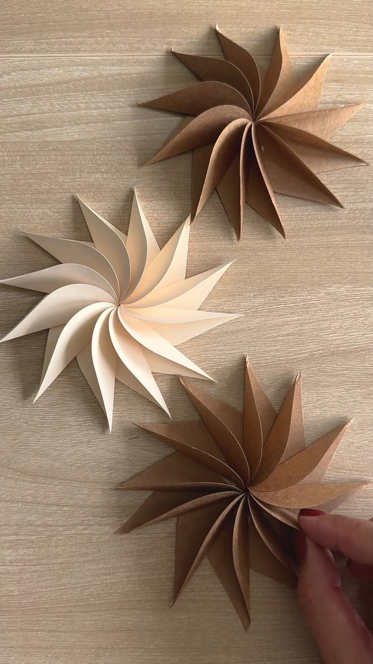 Cricut Christmas Balls: 14 DIY Ornaments for 2026 9 Three paper spiral star ornaments in brown and cream colors on a wooden surface.