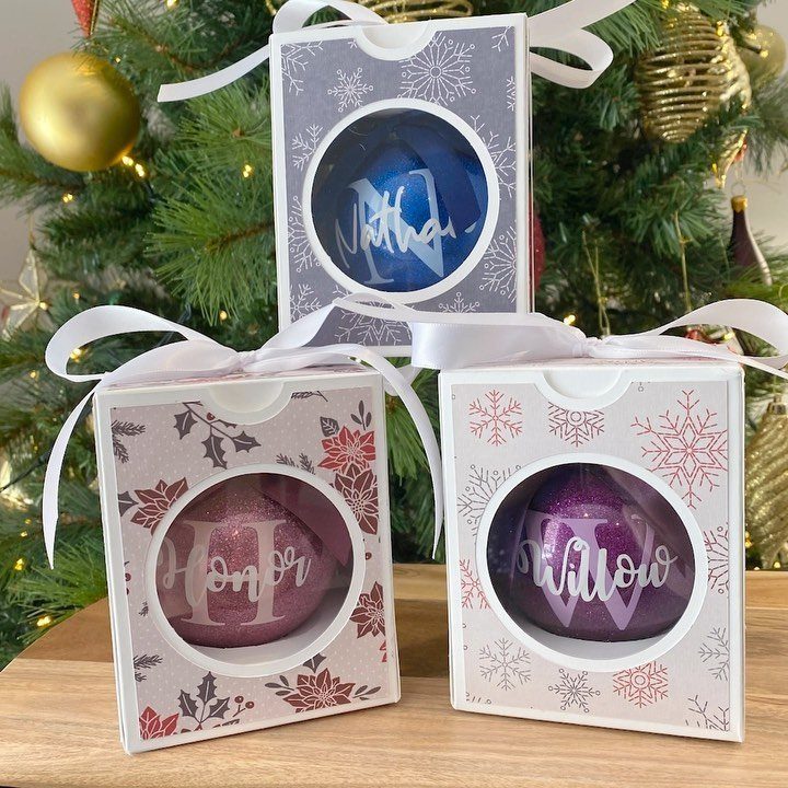 Cricut Christmas Balls: 14 DIY Ornaments for 2026 10 Three glittery glass ornaments with names inside decorative snowflake patterned gift boxes.