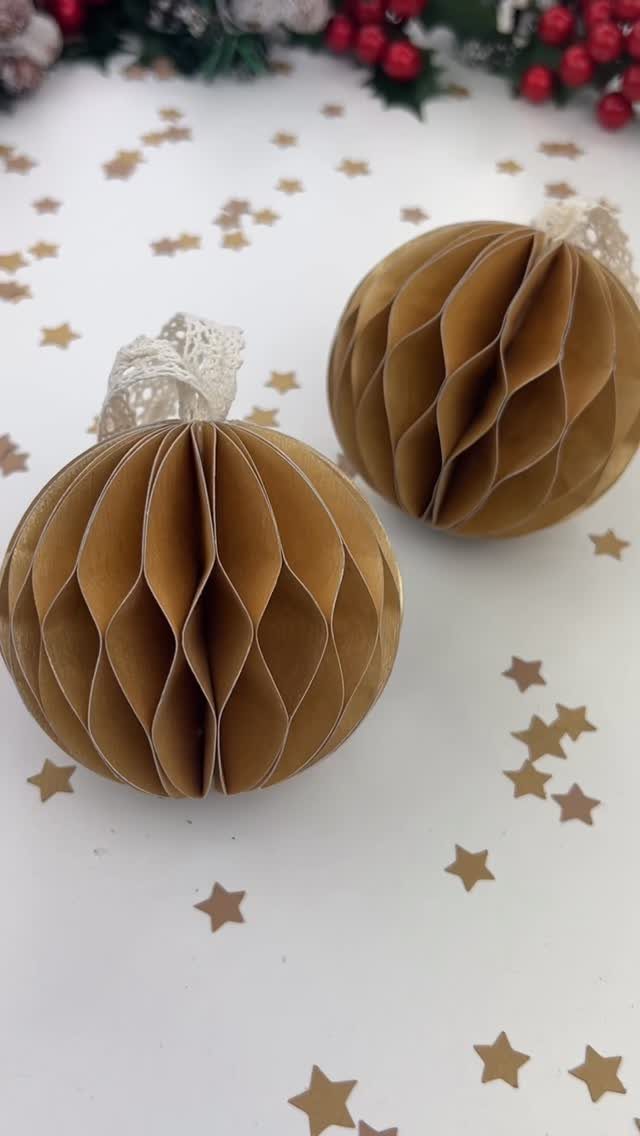 Cricut Christmas Balls: 14 DIY Ornaments for 2026 3 Two gold honeycomb paper ornaments resting on a white surface with gold star confetti.