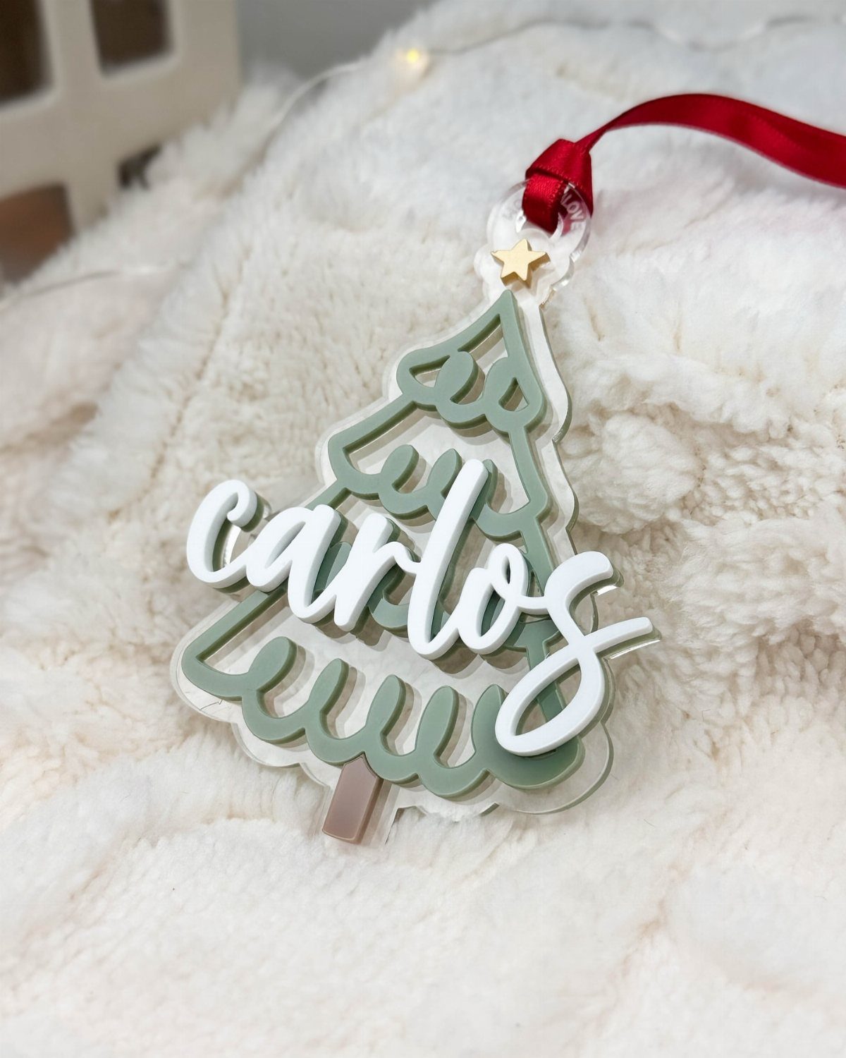 Cricut Christmas Balls: 14 DIY Ornaments for 2026 12 A personalized acrylic Christmas tree ornament with the name Carlos on a white fuzzy background.