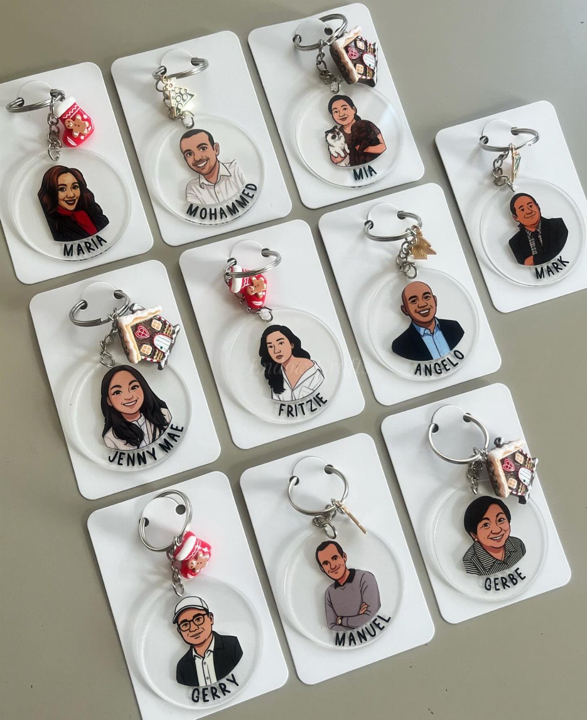 27 DIY Cheap Christmas Gifts for 2026 7 Multiple personalized acrylic keychains with cartoon portraits and small charms resting on white cards.