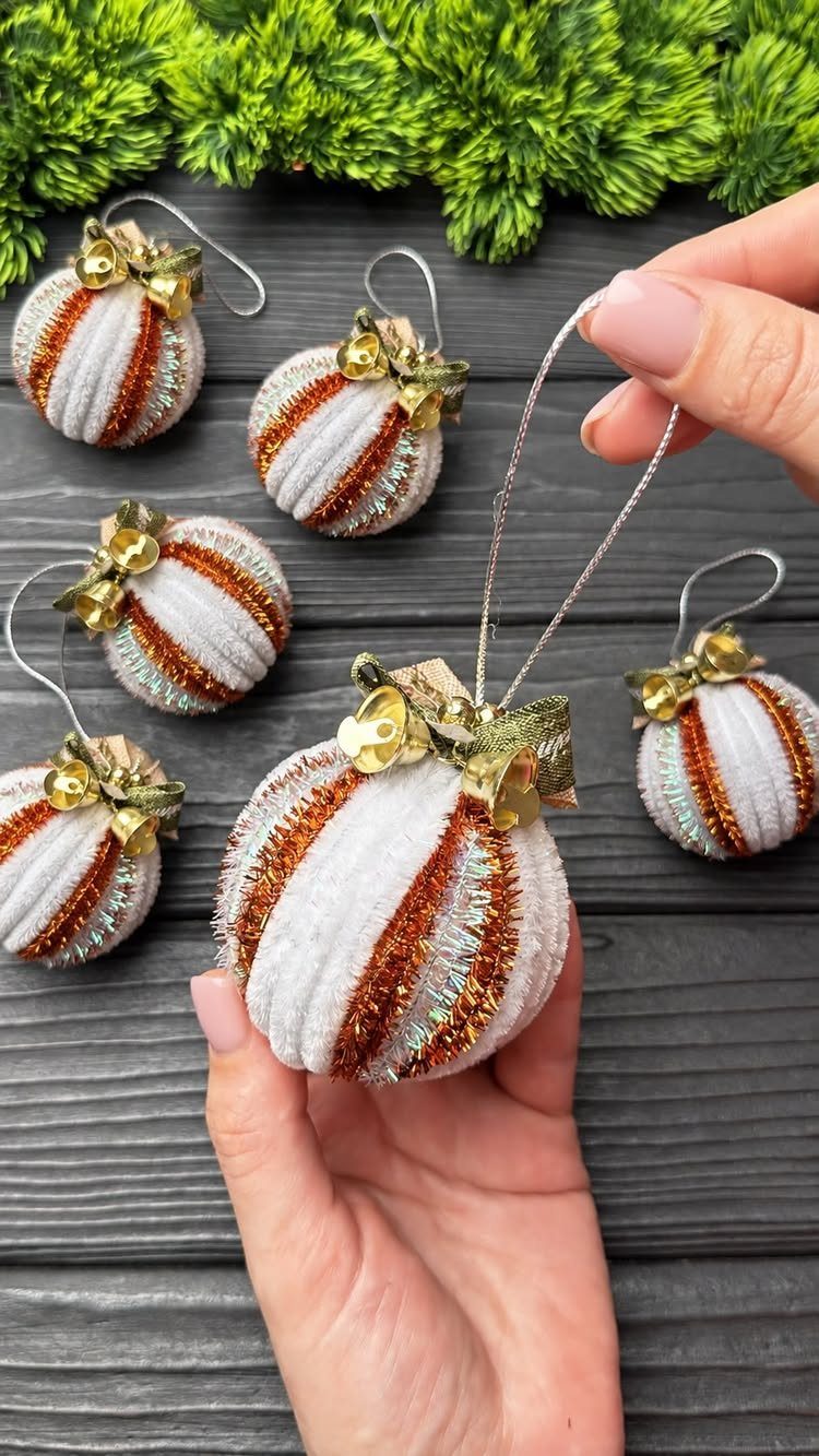 27 DIY Cheap Christmas Gifts for 2026 1 Hand holding a white and gold striped fabric Christmas ornament against a dark wood background.