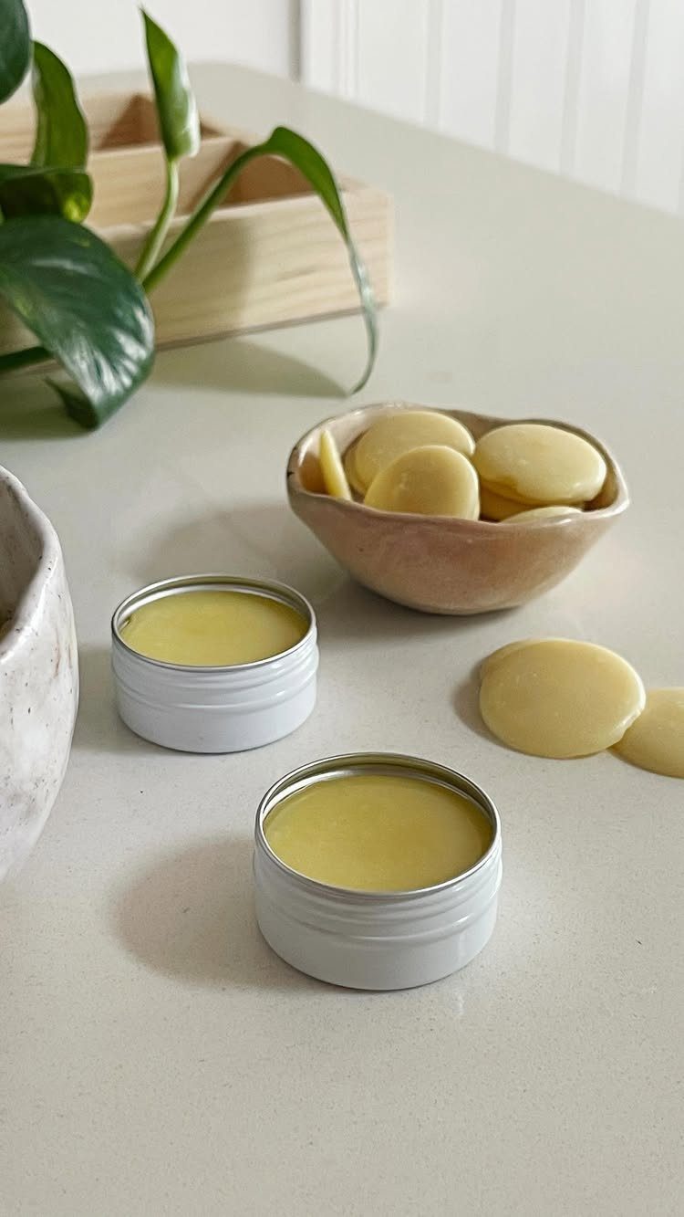 27 DIY Cheap Christmas Gifts for 2026 15 Two white metal tins filled with yellow lip balm on a light countertop.