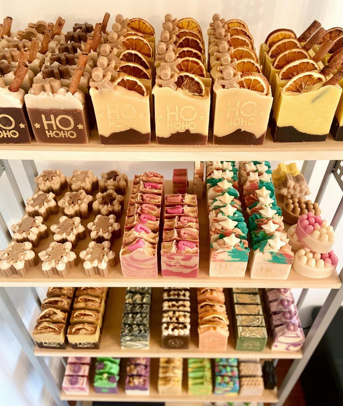 27 DIY Cheap Christmas Gifts for 2026 17 Artisanal handmade soap bars with dried fruit and cinnamon toppings displayed on white shelves.