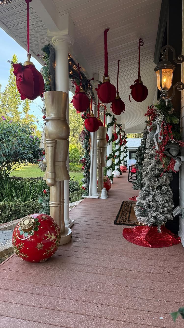 Christmas decorations on a porch featuring hanging red ornaments, a gold nutcracker, and festive garlands.
