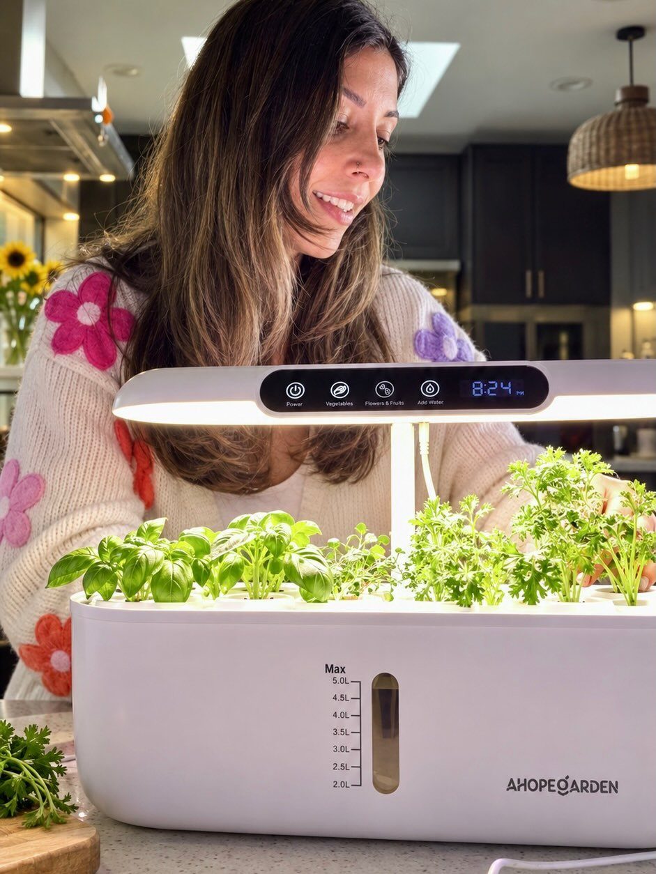 8 Foods for Growing Indoors: From Herbs to Hydroponic Tomatoes 1 A woman smiling at a white smart indoor garden with integrated grow lights and green plants.