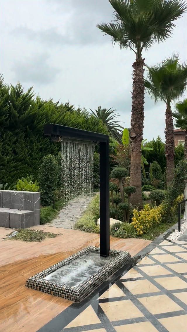 15 Huge Garden Design Ideas for Birds, Light, Night Paths and Still Water 1 A black metal water feature creates a falling water curtain into a mosaic-tiled basin in a garden.